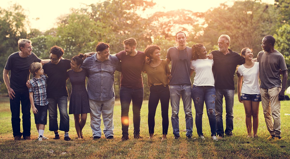 Group of people standing together in a line with sunshine behind them