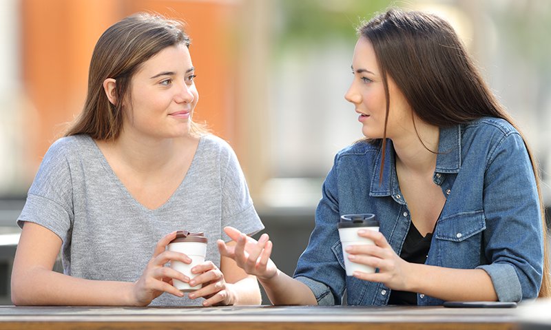Two young women having a conversation over coffee